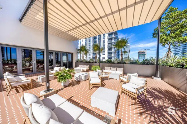 a view of a patio with couches and chairs under an umbrella