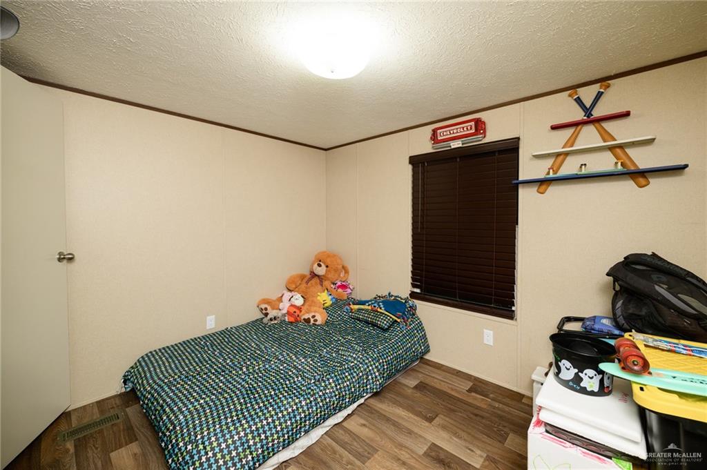 818 South 13th Street Alamo, TX 78516 - Photo 11 of 24 a bedroom with a bed and wooden floor
