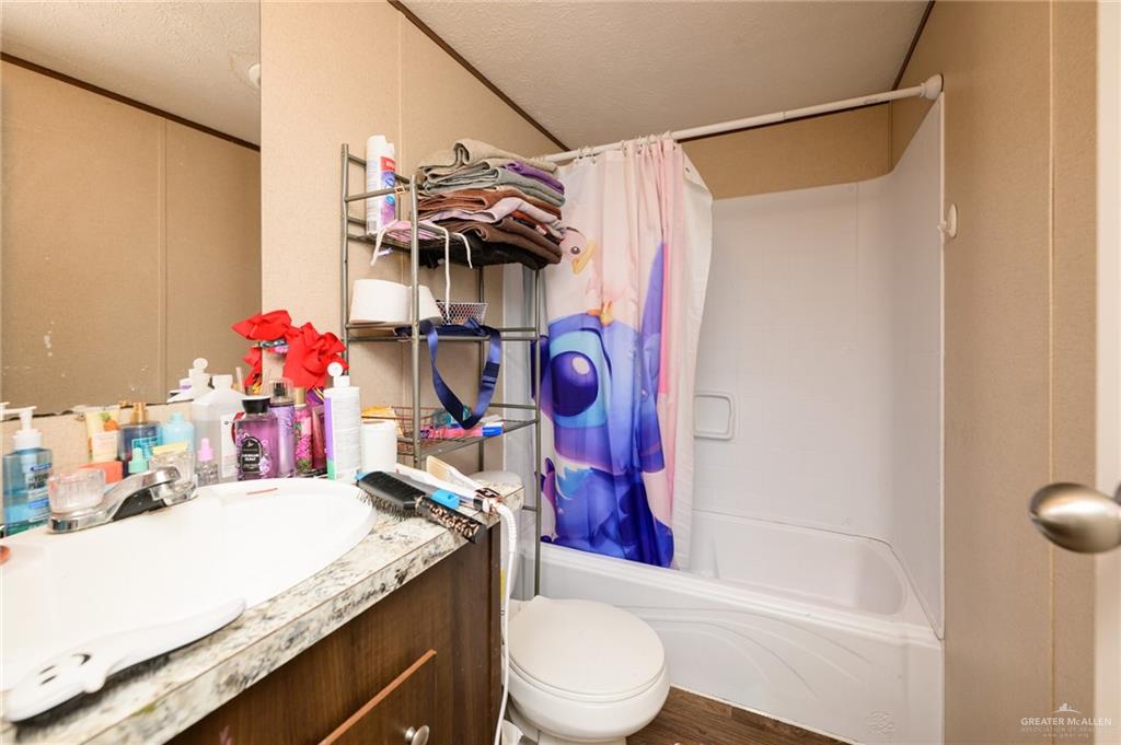 818 South 13th Street Alamo, TX 78516 - Photo 15 of 24 a bathroom with a granite countertop sink a toilet and shower curtain