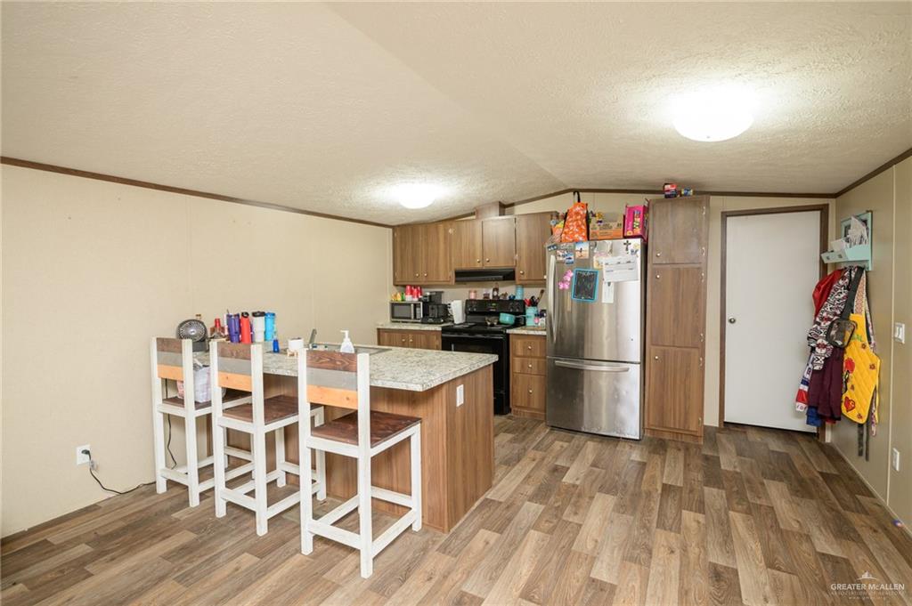 818 South 13th Street Alamo, TX 78516 - Photo 4 of 24 a kitchen with a refrigerator a microwave and a dining table