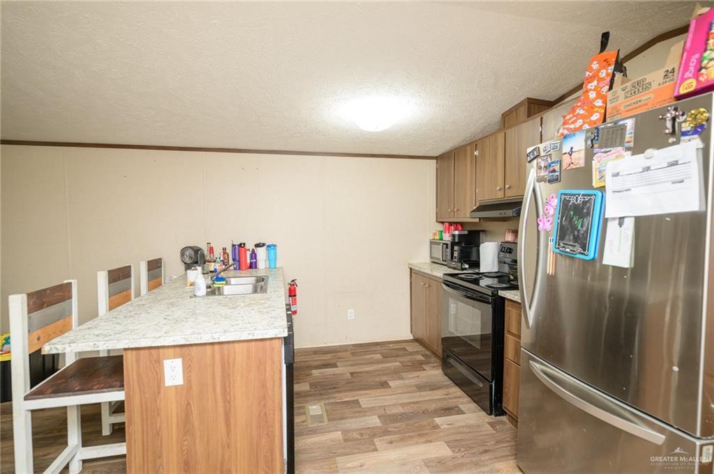 818 South 13th Street Alamo, TX 78516 - Photo 5 of 24 a kitchen with stainless steel appliances granite countertop a refrigerator a stove and a sink