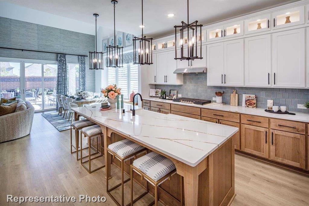 a kitchen with stainless steel appliances granite countertop a kitchen island a stove a refrigerator a sink dishwasher a dining table and chairs with wooden floor
