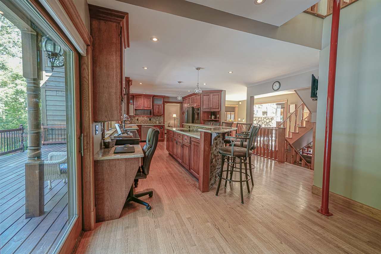 1052 South Harmony Road Oregon, IL 61061 - Photo 9 of 25 a kitchen with stainless steel appliances kitchen island granite countertop wooden floors and wooden cabinets