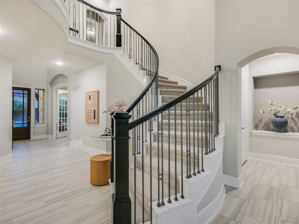 2610 Sunset Vista Circle, Unit 16 Spicewood, TX 78669 - Photo 8 of 28 Staircase featuring arched walkways, a towering ceiling, and wood finish floors
