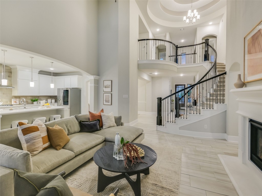 2610 Sunset Vista Circle, Unit 16 Spicewood, TX 78669 - Photo 10 of 28 Living area with arched walkways, a glass covered fireplace, a towering ceiling, recessed lighting, and a chandelier