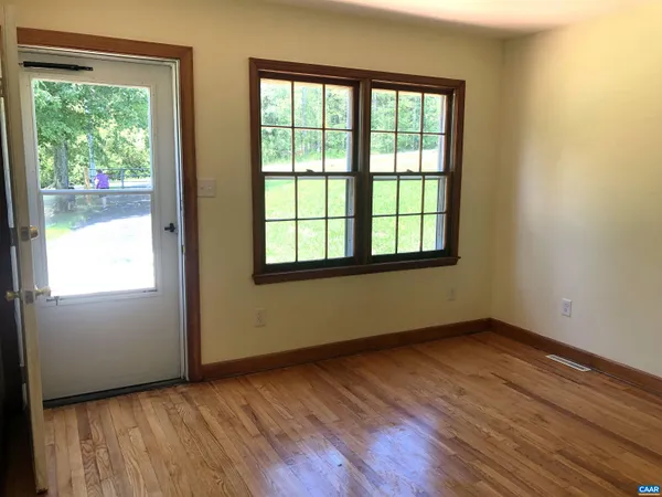 a view of an empty room with wooden floor and a window