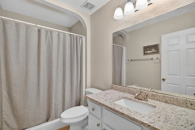 a bathroom with a granite countertop sink vanity mirror and toilet
