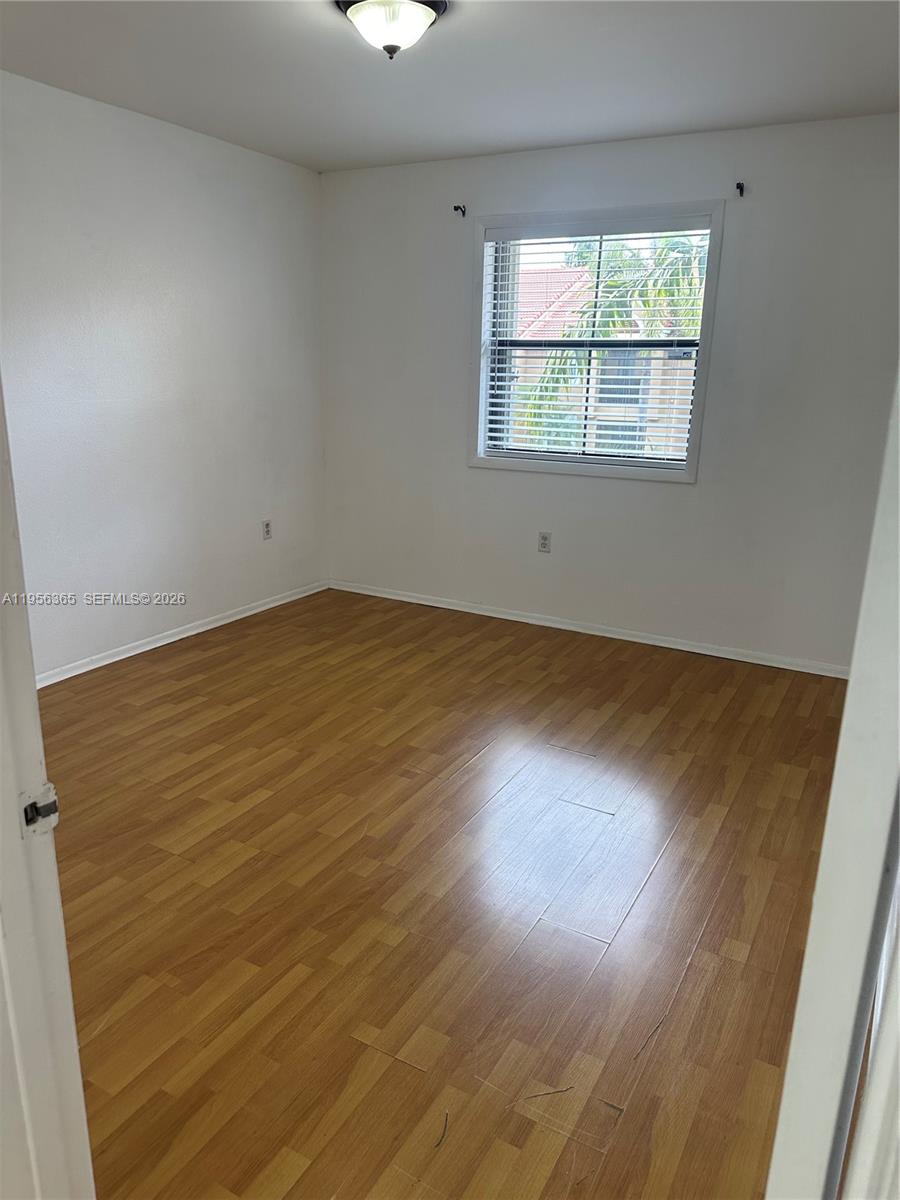 15560 Southwest 104th Terrace, Unit 625 Miami, FL 33196 - Photo 11 of 14 an empty room with wooden floor and windows