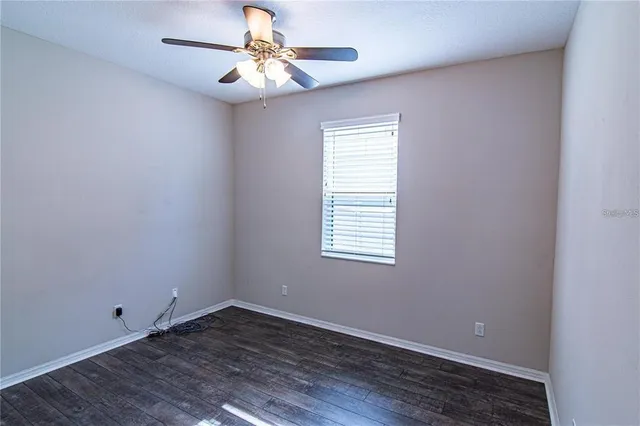 an empty room with a window and a fan