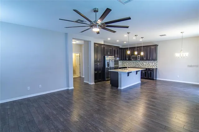 an open kitchen with a refrigerator and a stove top oven