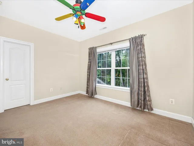 an empty room with windows and chandelier fan