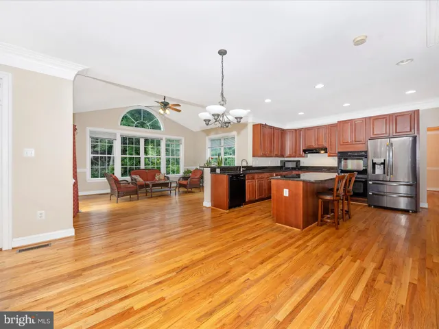 a open kitchen view with stainless steel appliances granite countertop a stove and a wooden floors