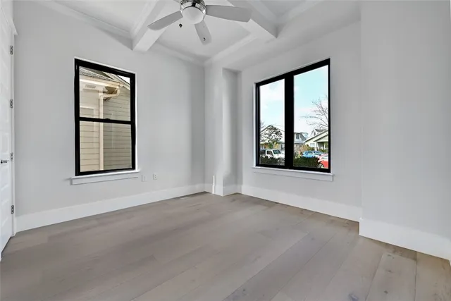 an empty room with windows and ceiling fan