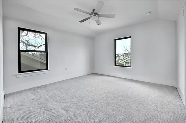 an empty room with windows and fan