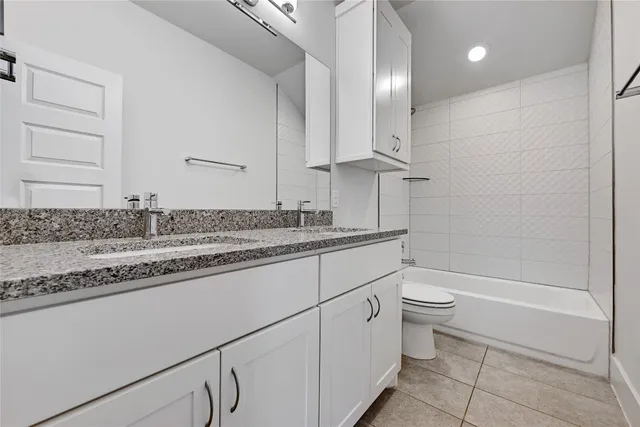 a bathroom with a granite countertop sink a toilet and bathtub