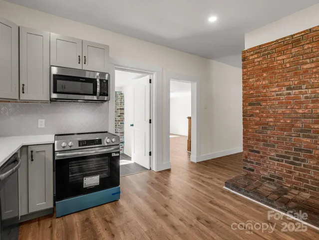 a kitchen with stainless steel appliances a stove a microwave and a hard wood floor