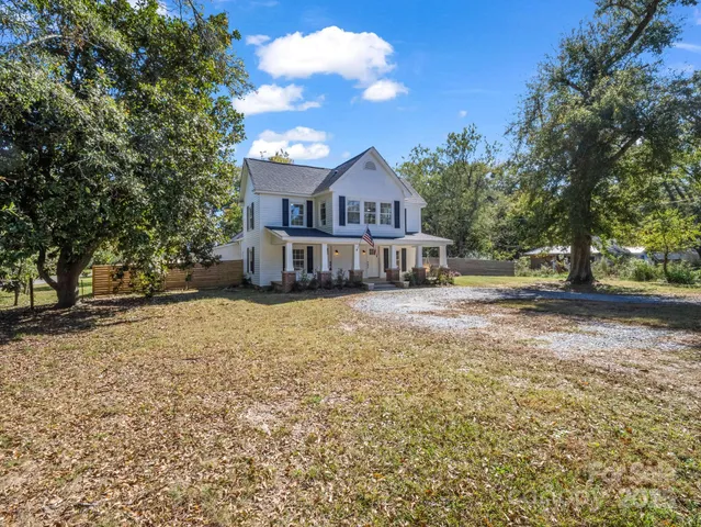 a front view of a house with a yard and large trees