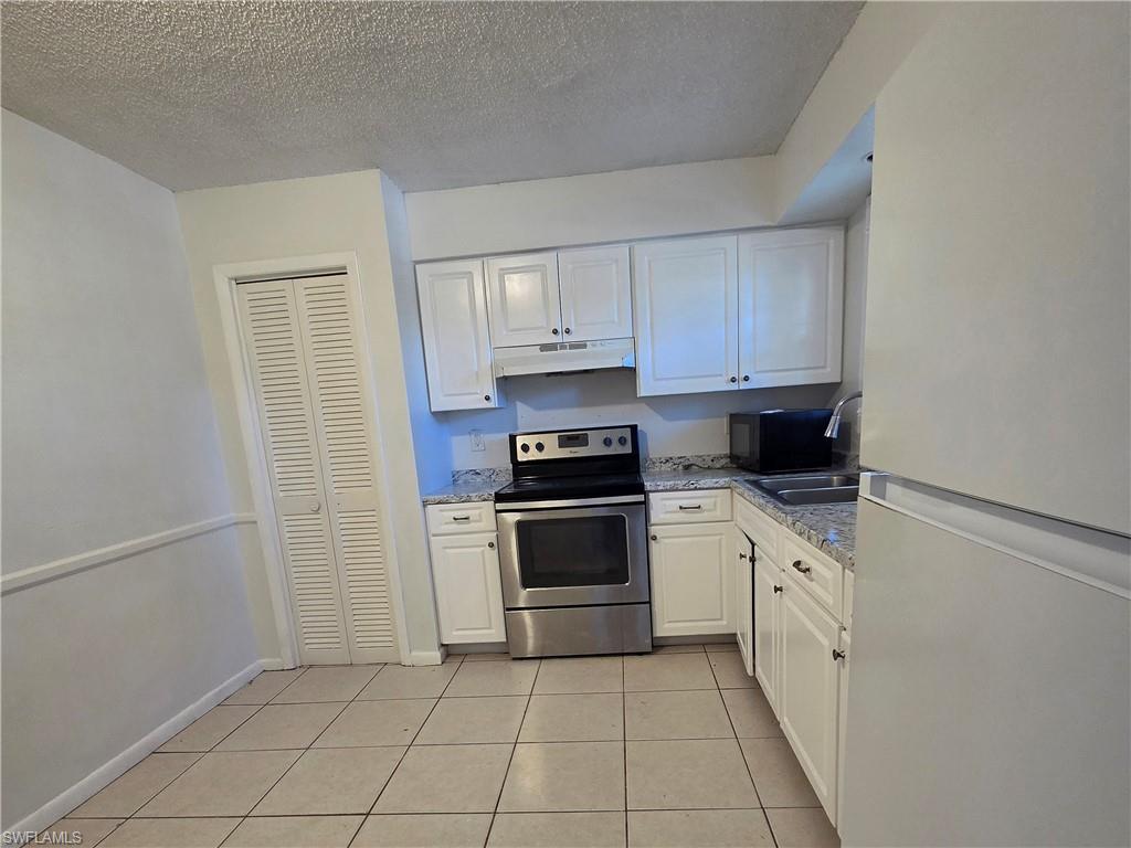3325 Airport Road North, Unit G7 Naples, FL 34105 - Photo 2 of 13 a kitchen with white cabinets and appliances