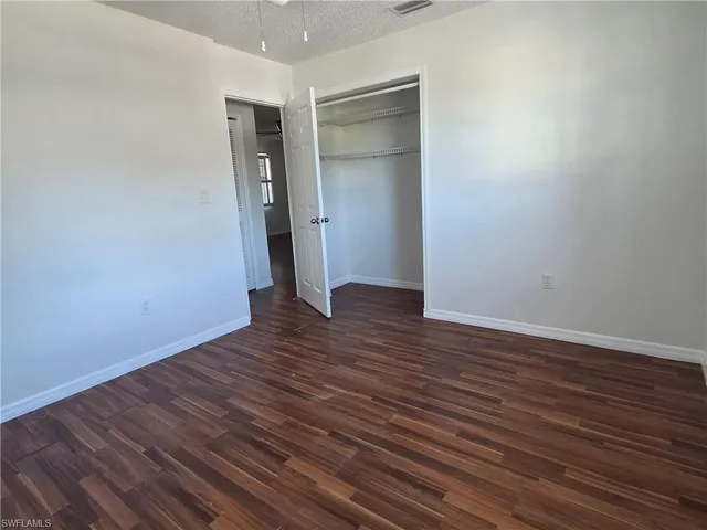a view of an empty room with wooden floor and closet