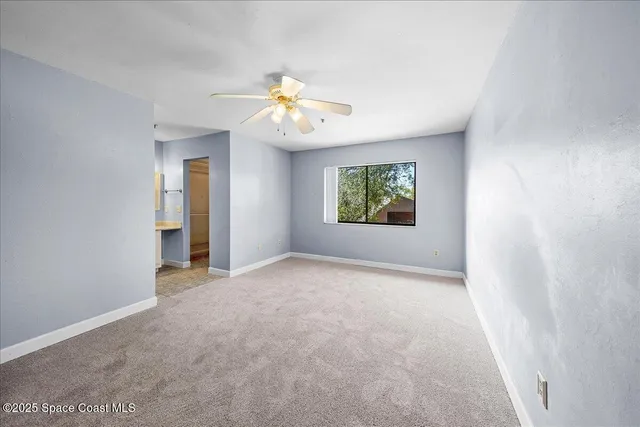 an empty room with windows and ceiling fan
