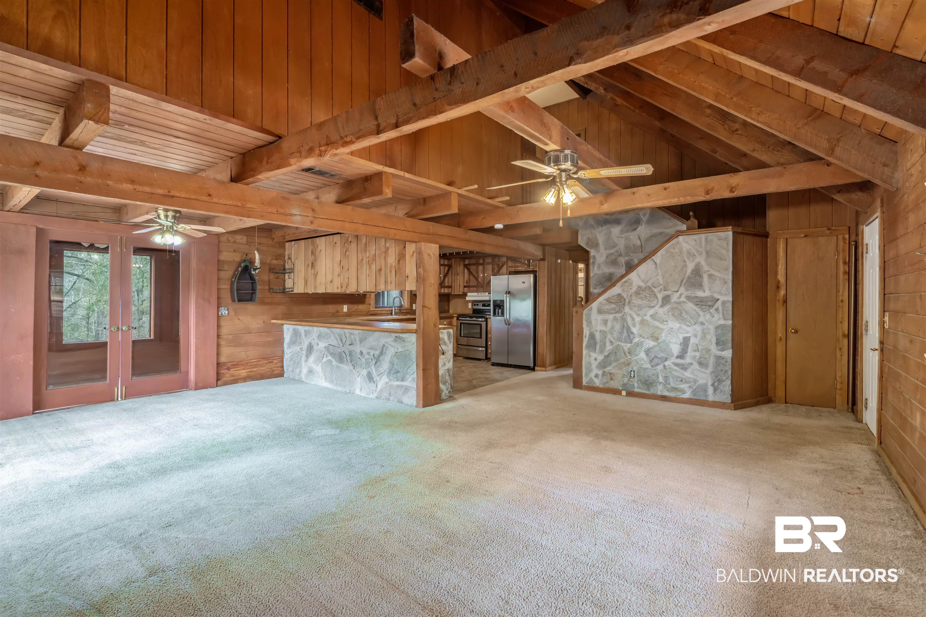4131 Greaves Road Eight Mile, AL 36613 - Photo 5 of 39 Unfurnished living room featuring wooden walls, lofted ceiling with beams, light colored carpet, ceiling fan, and french doors