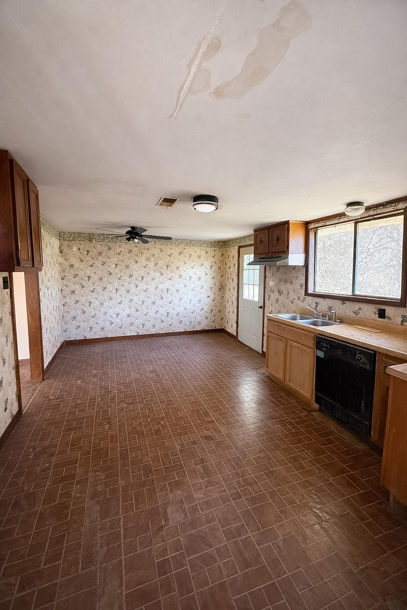 7394 Benjestown Road Millington, TN 38053 - Photo 4 of 6 Kitchen with brick patterned flooring, wallpapered walls, dishwasher, light countertops, and a textured ceiling