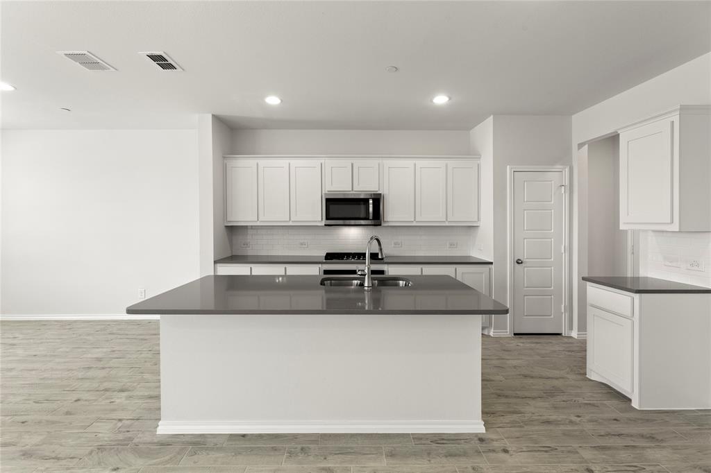 5414 East Runnel Road Royse City, TX 75189 - Photo 10 of 26 a kitchen with kitchen island a sink a stove a refrigerator and white cabinets