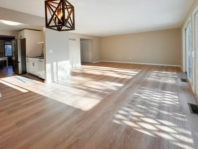 a view of an empty room with wooden floor and a fireplace