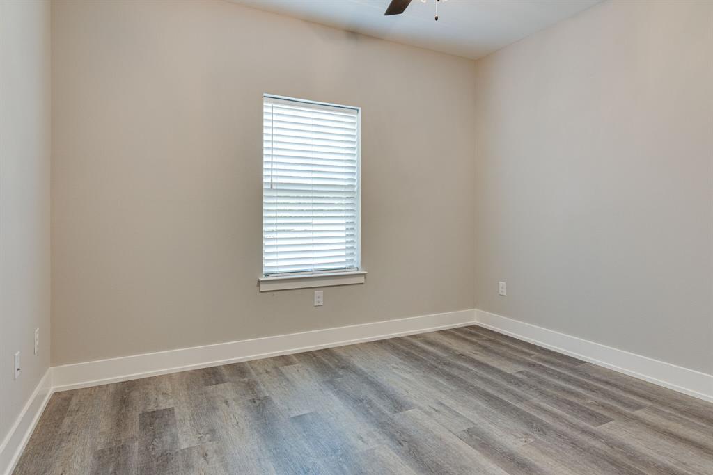 115 West Jones Street, Unit 103 Krum, TX 76249 - Photo 14 of 21 wooden floor in an empty room with a window