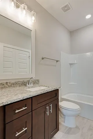 a bathroom with a granite countertop sink a toilet and a bathtub