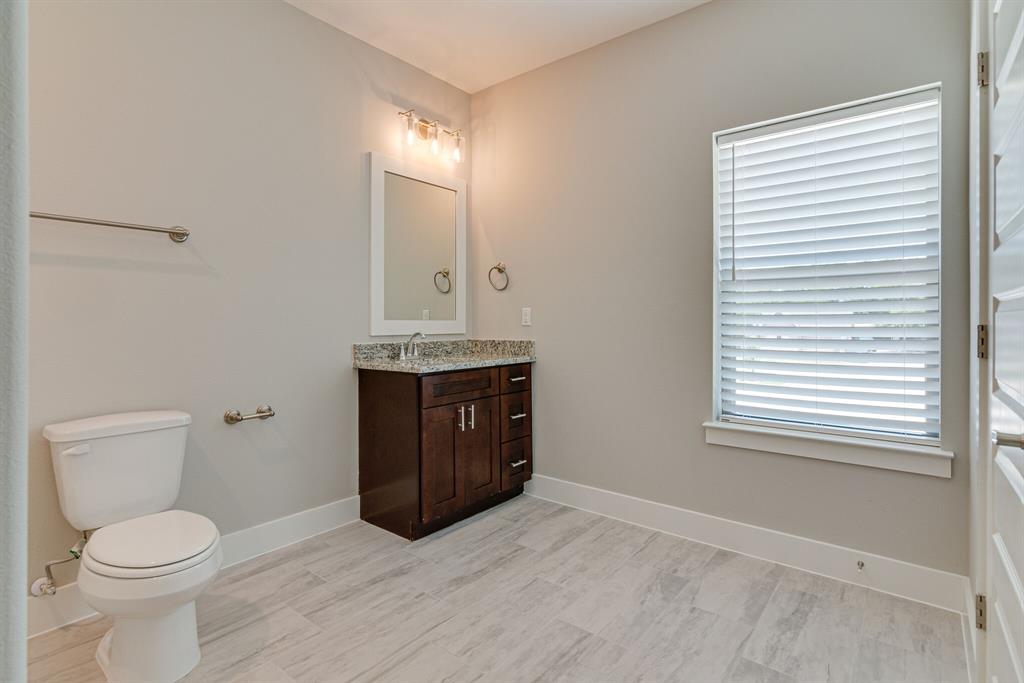 115 West Jones Street, Unit 103 Krum, TX 76249 - Photo 19 of 21 a bathroom with a toilet sink and mirror