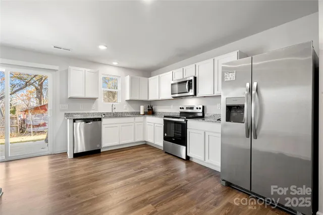 a kitchen with granite countertop a refrigerator stove top oven and sink