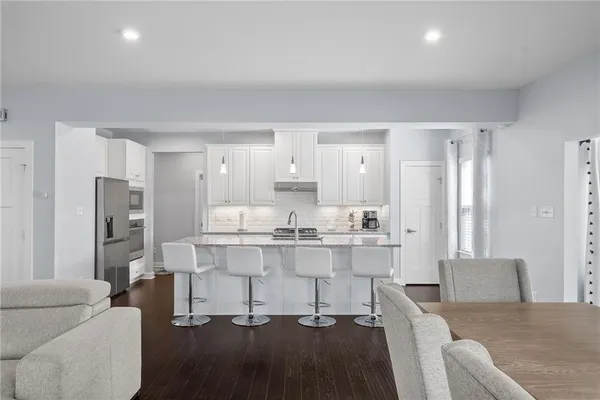 a living room with stainless steel appliances kitchen island granite countertop furniture and a refrigerator