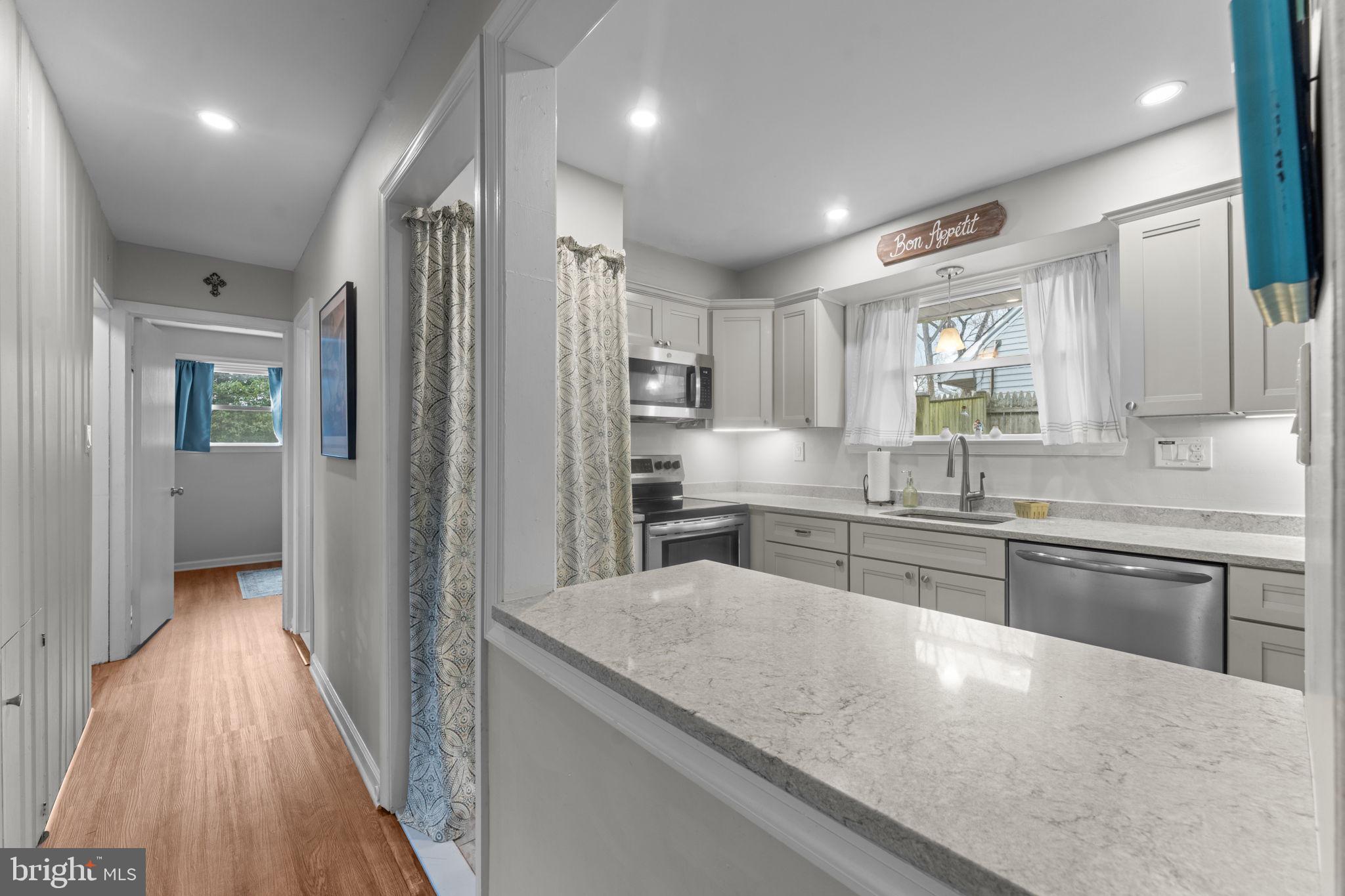 1806 Tilton Drive Silver Spring, MD 20902 - Photo 19 of 54 a kitchen with stainless steel appliances granite countertop a refrigerator a sink dishwasher a stove and white countertops with wooden floor