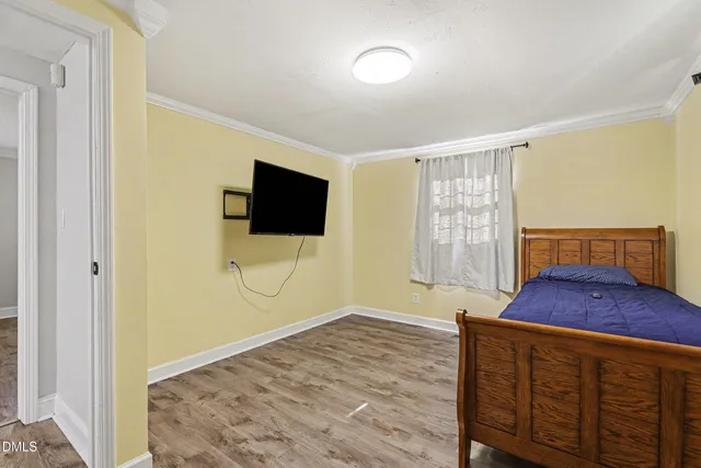 a living room with a bed and a walk in closet with wooden floor