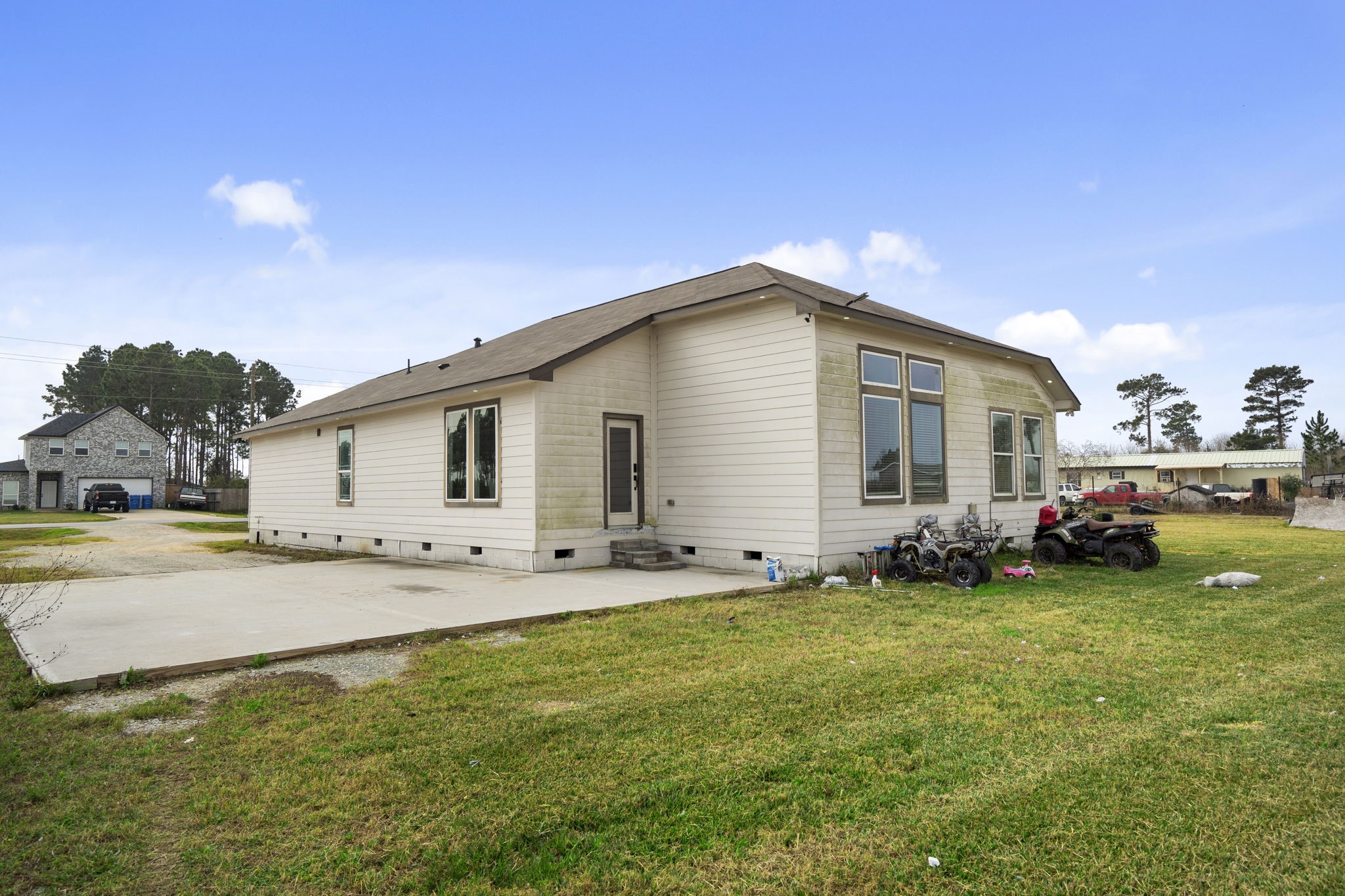 1294 County Road 5100 Cleveland, TX 77327 - Photo 25 of 27 Rear exterior of the home featuring a concrete patio and open yard area with room for future landscaping or outdoor use.