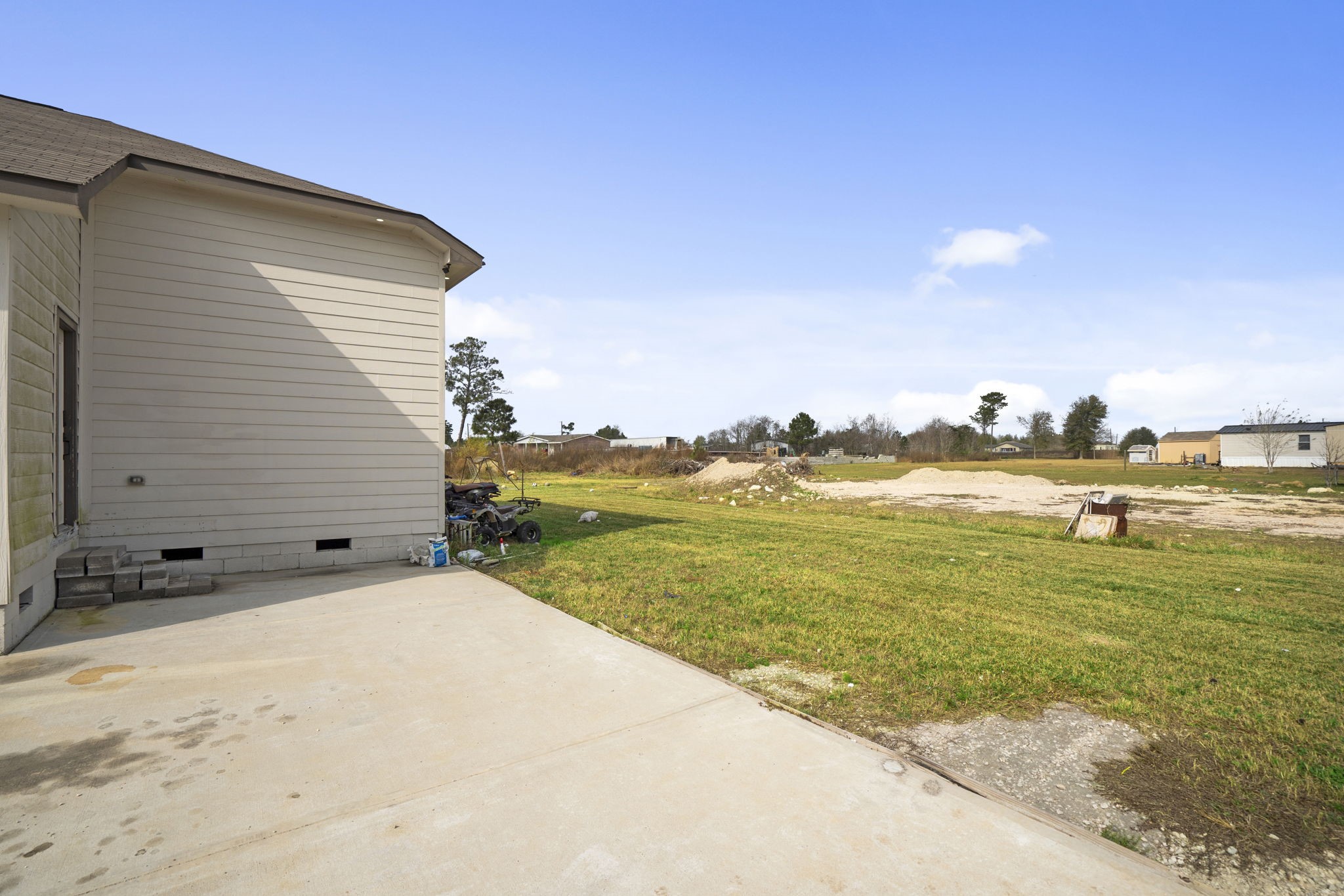 1294 County Road 5100 Cleveland, TX 77327 - Photo 26 of 27 Side yard with open green space and easy access from the home, offering flexibility for outdoor storage or simple yard improvements.