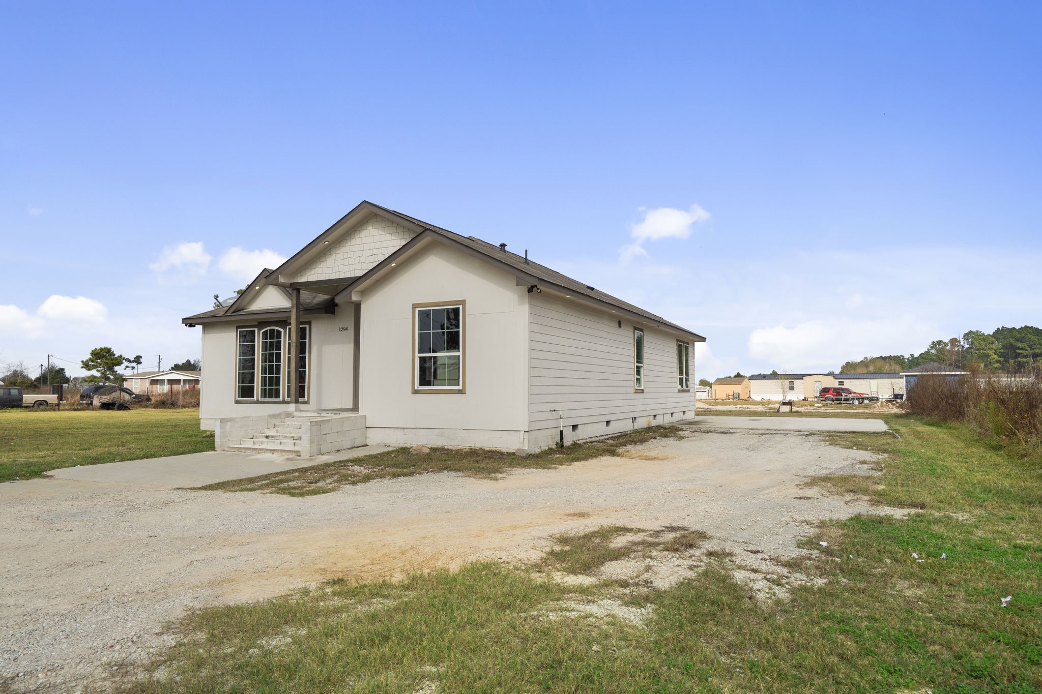 1294 County Road 5100 Cleveland, TX 77327 - Photo 27 of 27 Additional exterior view showing the home’s layout, driveway access, and surrounding open space.