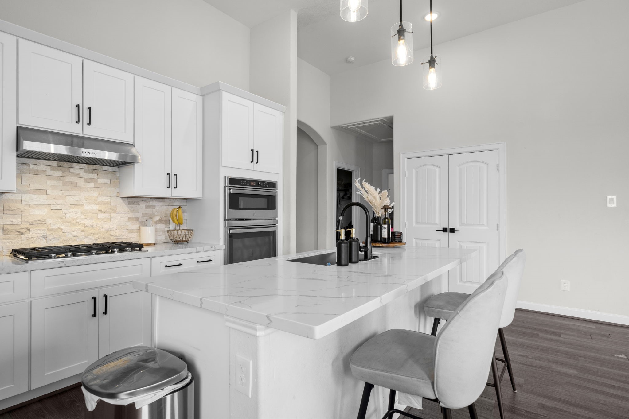 1294 County Road 5100 Cleveland, TX 77327 - Photo 9 of 27 This stunning kitchen showcases a large island with smooth quartz-style countertops, complemented by built-in appliances and abundant cabinetry. The open layout flows seamlessly, making it ideal for gatherings, meals, and daily routines alike.