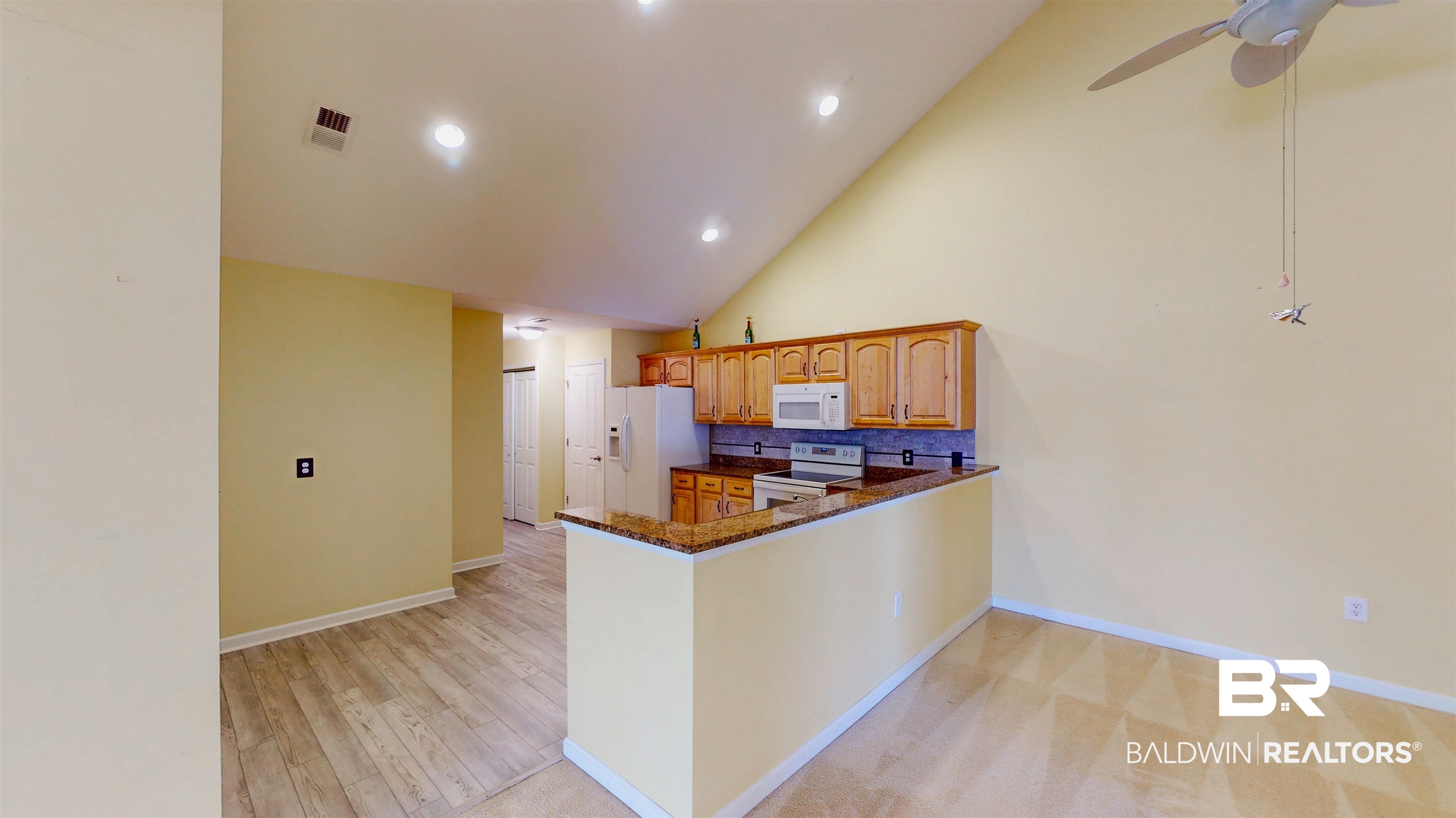 303 Wyld Palms Drive, Unit 303 Foley, AL 36535 - Photo 11 of 36 Kitchen with white appliances, high vaulted ceiling, a peninsula, dark stone counters, and recessed lighting
