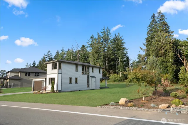a view of a white house with a big yard and large trees