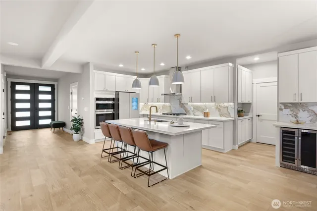a large kitchen with kitchen island a sink white cabinets and stainless steel appliances