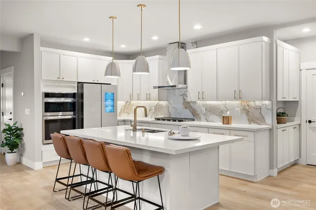 a kitchen with stainless steel appliances kitchen island granite countertop a table chairs and a refrigerator