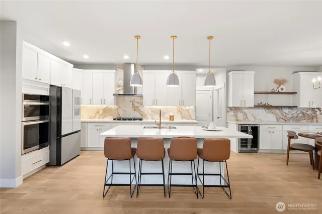 a dining hall with stainless steel appliances kitchen island granite countertop a dining table chairs and a refrigerator