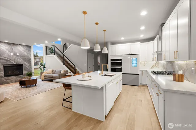 a kitchen with stainless steel appliances kitchen island a stove a sink dishwasher and a fireplace with wooden floor