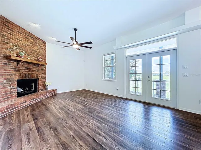 wooden floor in an empty room with a fireplace and a window