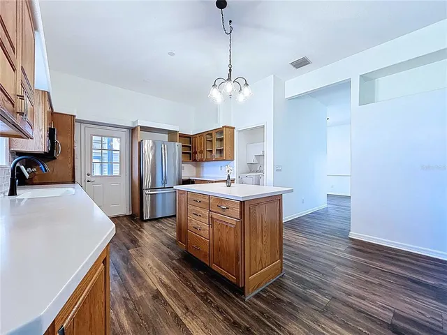 a kitchen with stainless steel appliances granite countertop a sink a stove top oven a chimney wooden floor and cabinets