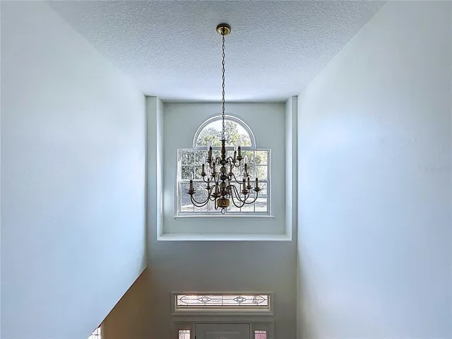 a view of a hallway with windows and chandelier