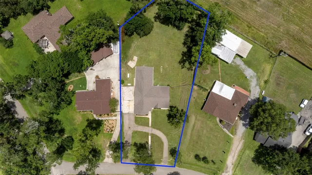 an aerial view of a residential houses with outdoor space and trees