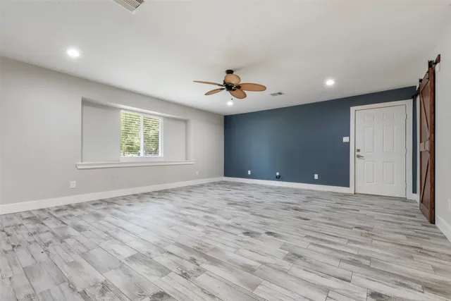 an empty room with wooden floor ceiling fan and windows